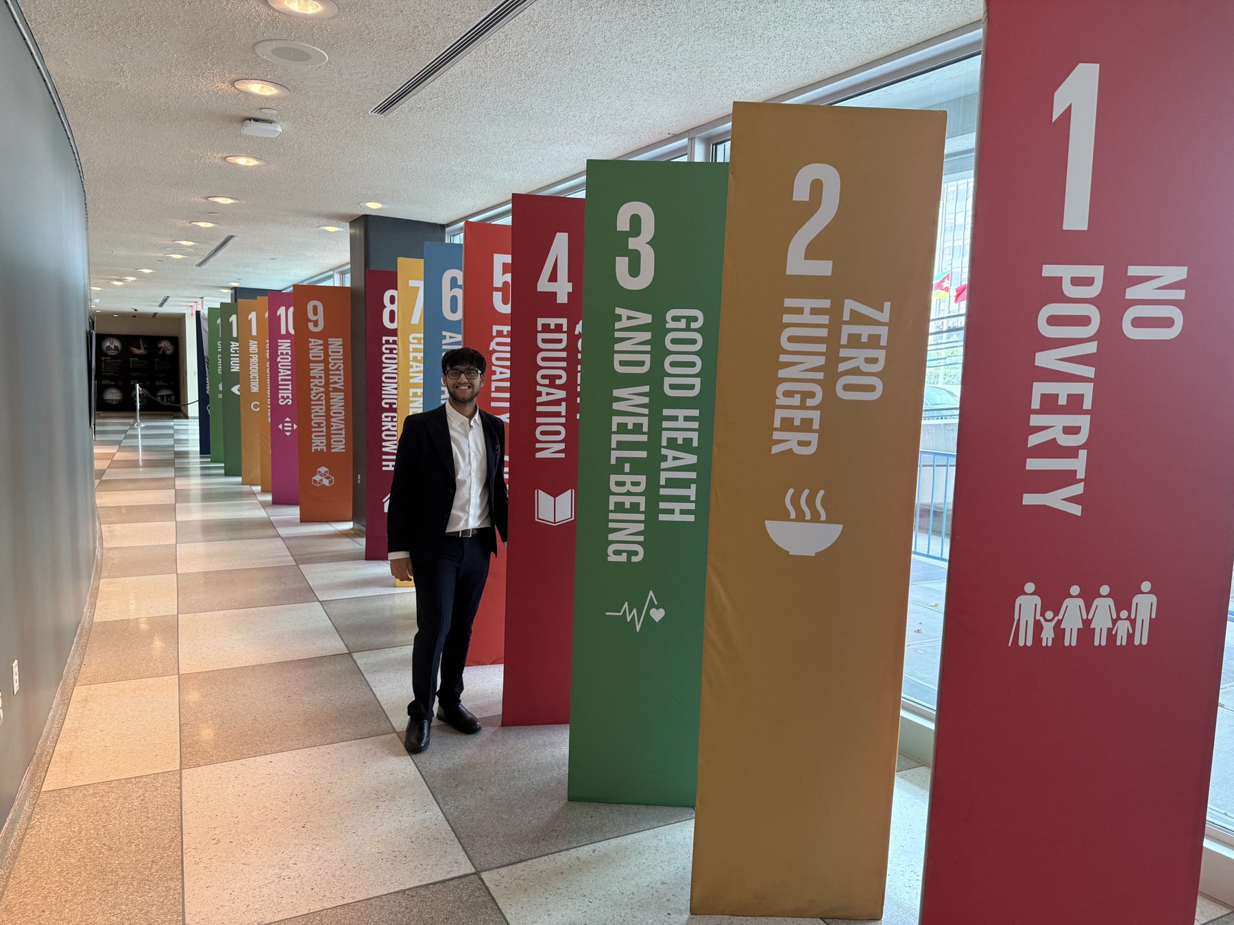 Rhythm Bazari beside the Sustainable Development Goals display at UN Headquarters
